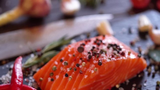 Raw salmon steak with spices and herbs. Camera moves around the object. 4K video.