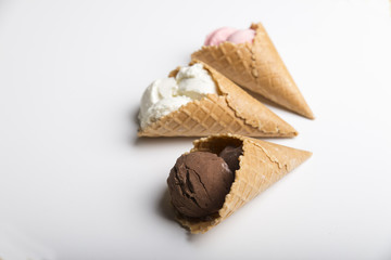 Variety of ice cream scoops in cones with chocolate, vanilla and strawberry