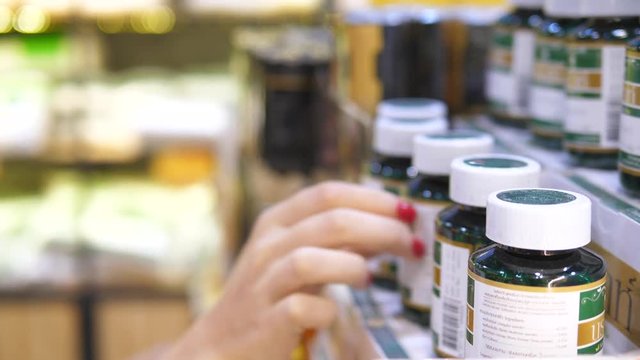 Closeup Of Female Hand Choosing Medicine At Pharmacy