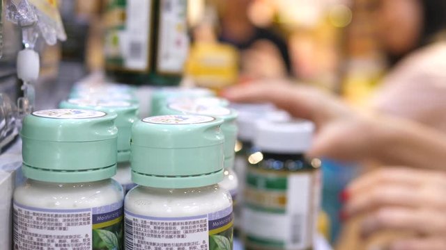 Woman Customer Choosing Food Dietary Supplement In Pills At Drugstore
