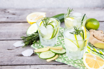 Homemade Lemonade with Lime, Rosemary, Ginger, Cucumber and Ice on a Wooden Background