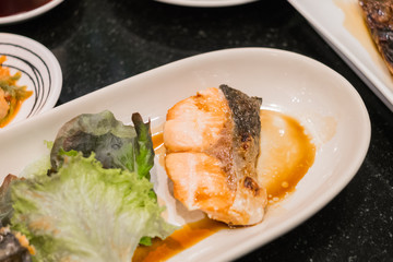 salmon grilled served on white dish with vetgetable.