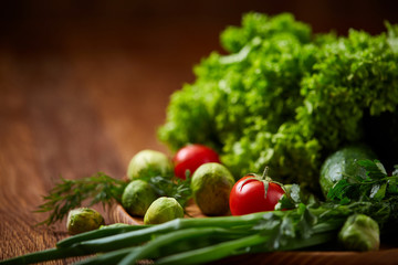 Vegetarian still life of fresh vegetables on wooden plate over rustic background, close-up, flat lay.