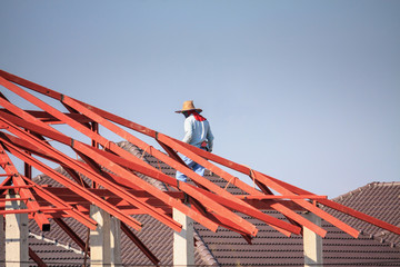 welder workers installing steel frame structure of the house roof at building construction site