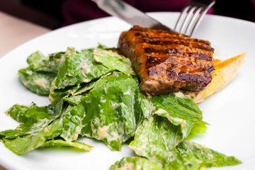 Closeup of grilled beef steak served on toasts with fresh salad