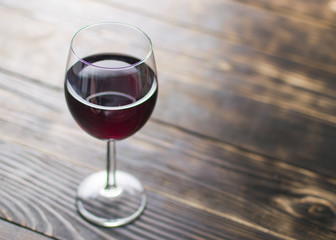 A glass of wine on a wooden background.
