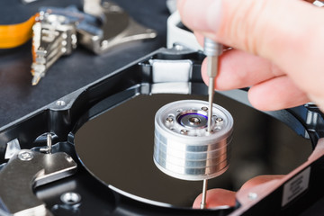Repairman disassembling hard disc drive close-up