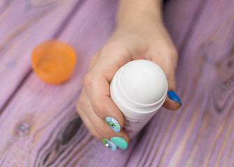 Female deodorant in hand on a wooden background.