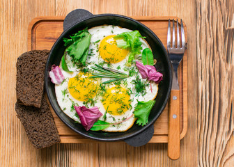 fried eggs in a frying pan and greens.
