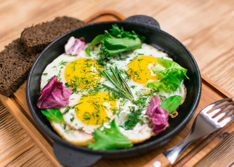 fried eggs in a frying pan and greens.