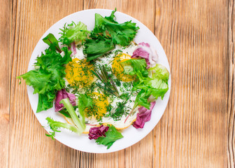 Fried eggs with greens on a plate on a wooden background. Healthy breakfast.