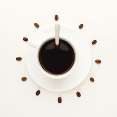 Black coffee cup and roasted beans forming clock dial isolated on white