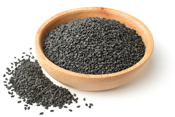 dried black sesame seeds in the wooden plate, isolated on white