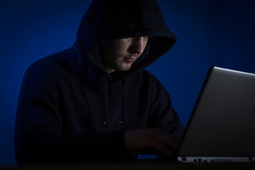 A young man in a hood behind a laptop