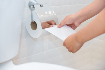 Close up of A woman hand using toilet paper in white and clean toilet room