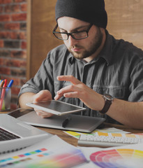 Young creative artist of web design in hat with graphic tablet in modern loft office