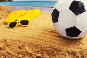 football in the sand with sandals at the beach