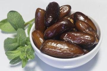 Dates, in white dish, ready to eat, white background. Close-up.
