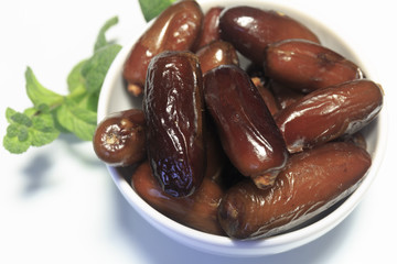 Dates, in white dish, ready to eat, white background. Close-up.