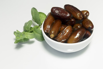 Dates, in white dish, ready to eat, white background. Close-up.