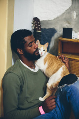 Man with black beard and dark skin sitting at home with white-orange funny cat