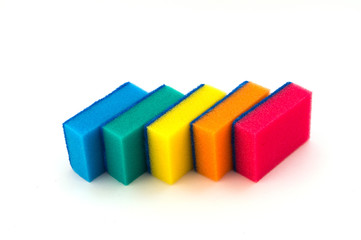 Пять разноцветных поролоновых губок для мойки и чистки от загрязнений на белом фоне, уложенных в один ряд зигзагом.
