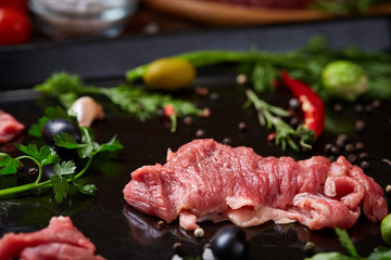 Still life of raw beef meat with vegetables on wooden plate over vintage background, top view, selective focus