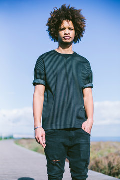 Outdoor portrait of young man with dark skin, mixed race, big African hair