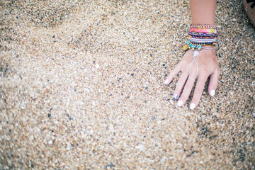 woman hand with bracelets on sea beach