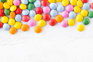 Colorful round candies on white rustic wooden background  with copy space. Different Small colored candies. Top view..