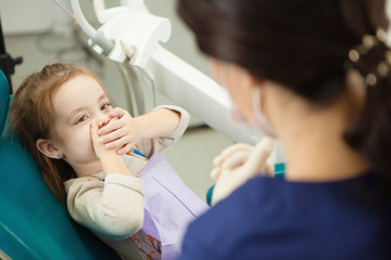 Kid afraid of procedure closes mouth with hands