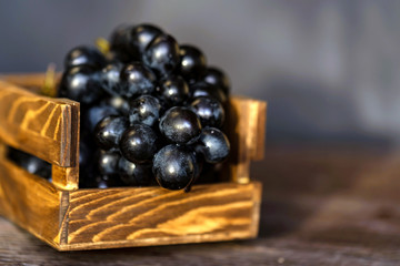 Bunch of a dark grapes in wooden box close