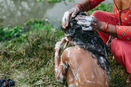 Mother washing hair of her daughter outdoor. Dark skin, Asian poor village in Nepal