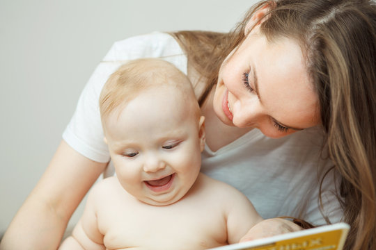 Mother reading to little infant colorful book with fairy tales.