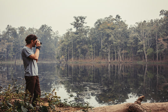Traveller photographer standing and do pictures of tropical lake landscape by compact professional camera
