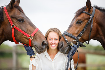 Fototapeta premium Young rider girl having fun with two her horses. Equestrian sport concept background