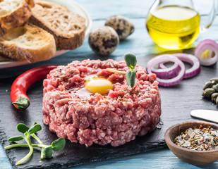 Steak tartare served with raw quail egg yolk, capers and bread. Meat dish.