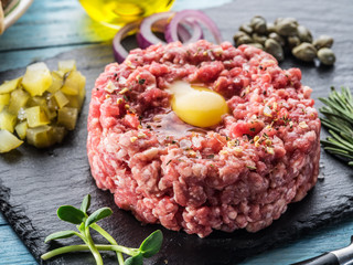 Steak tartare served with raw quail egg yolk and other tartare ingredient. Top view.