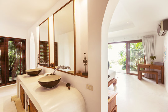 Bathroom and bedroom interior in luxury villa. Big windows, glass door to veranda outdoor
