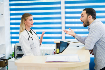 Man talking to female receptionist at hospital