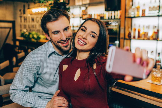 A picture where girl is making selfie with her boyfirend. THey are smiling and looking to the camera. THis couple is nice and very lovely.