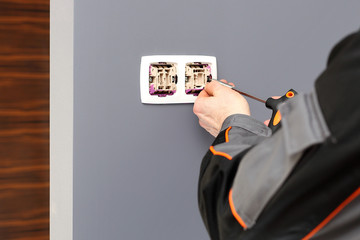 Elektryk montuje gniazdko elektryczne w ścianie. - obrazy, fototapety, plakaty