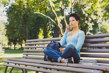 Fototapeta premium Pensive woman speaking on mobile phone in the park