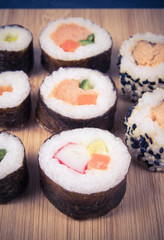 Various kinds of sushi on the wooden background.