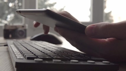 Close up on hands of young man using tablet while sitting computer keyboard and mouse. Freelancer photographer working and using tablet for communication with clients. - Powered by Adobe