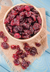 Dry cranberries fruit in the bowl, on the wood background.