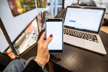 woman hold phone with white screen. laptop on background. freelancer concept. copy space
