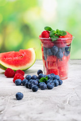 Plastic cup full of fresh cut fruits and berries