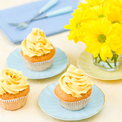 Cupcake with yellow cream decoration and bouquet of yellow chrysanthemum in small glass.