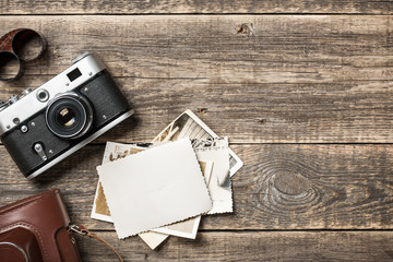 Retro camera, film and old paper photos on wooden background